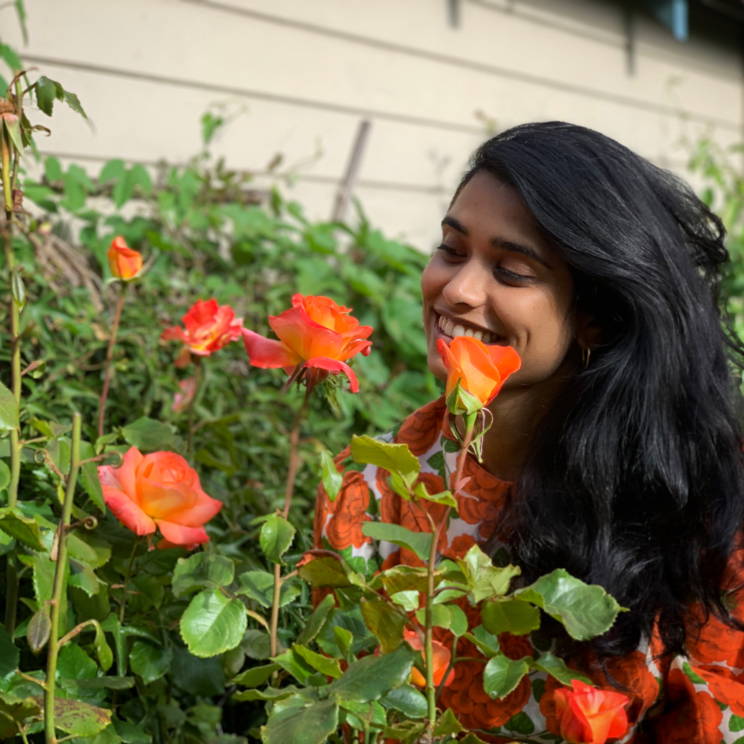 Image of a woman with long hair behind orange flowers.
